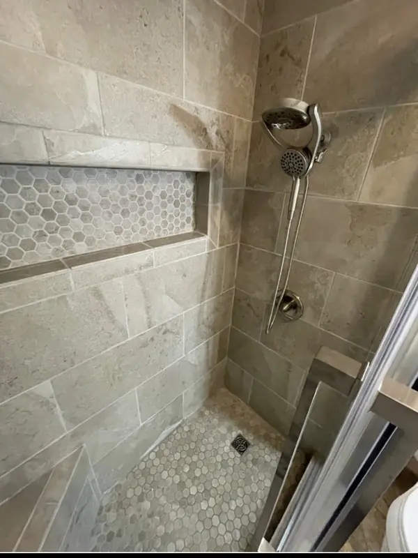Stone tile shower with hexagon mosaic niche