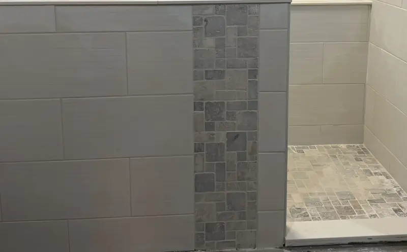 Stone mosaic strip detail with large-format wall tile